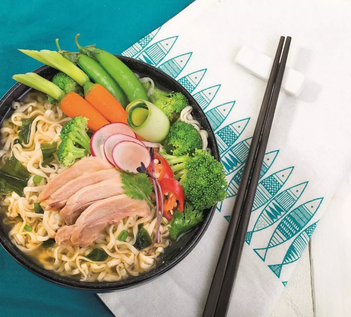 Nguyên liệu: 1 gói mì Udon Sưki Sưki; 50gr thịt đùi gà; 20gr đậu Hà Lan; 30gr bông cải xanh; 20gr cà rốt baby; 5gr rong biển; Ớt sừng, ngò rí.